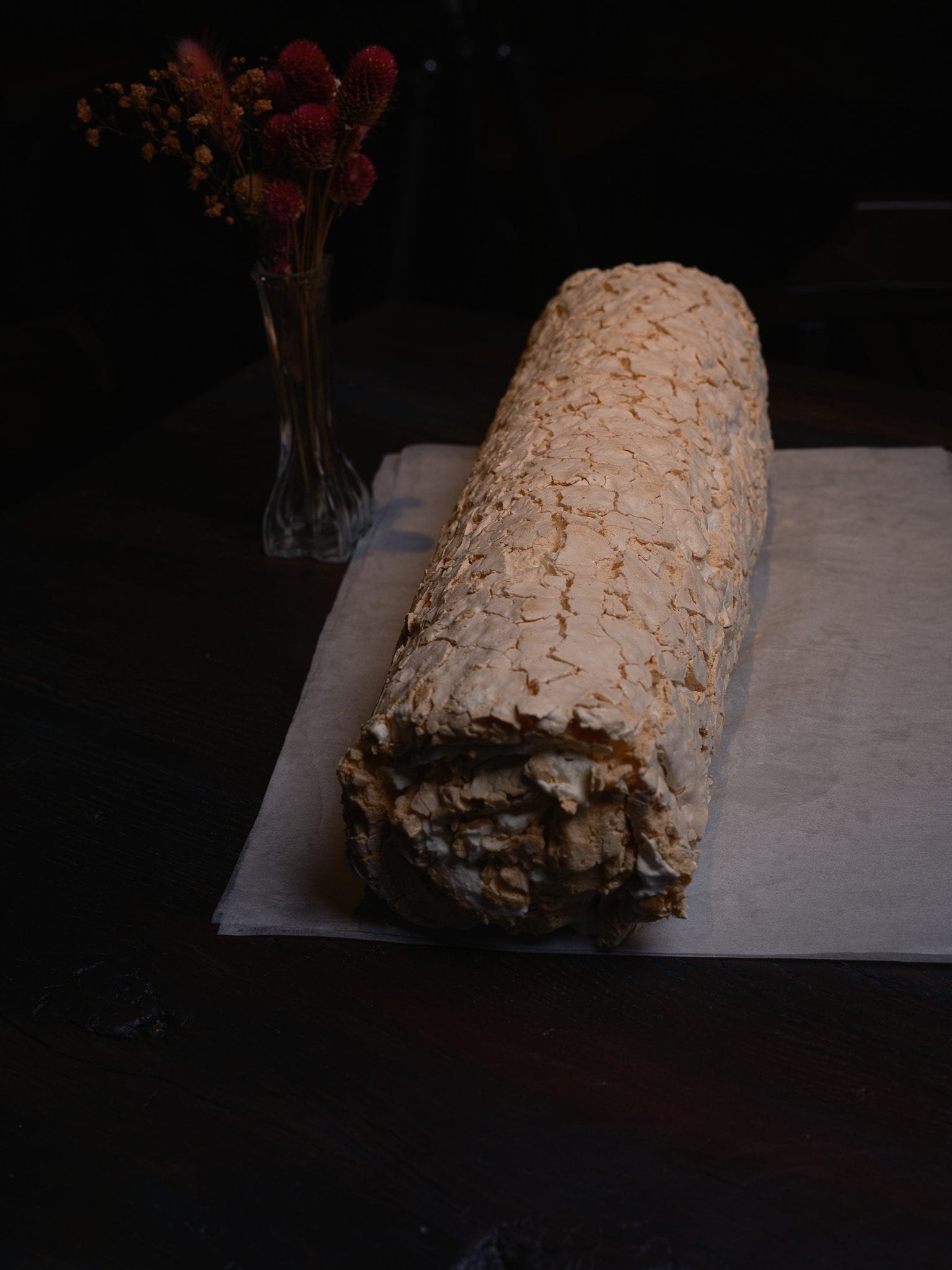 Whole meringue roll at GUSI on parchment beside dried flowers — Eastern European dessert in Greenwich Village
