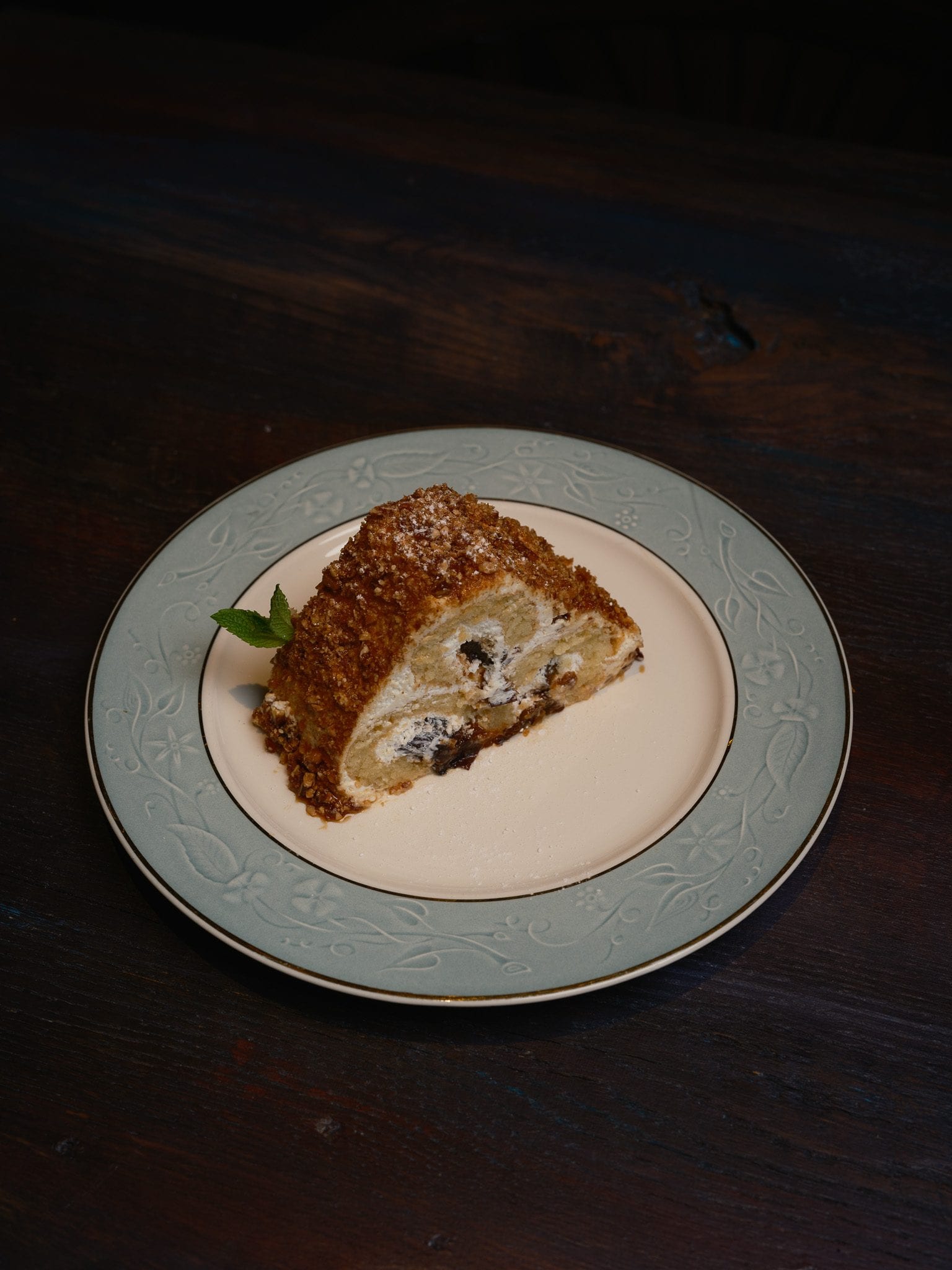 Slice of grillage cake at GUSI with caramelized nuts and cream on a vintage plate